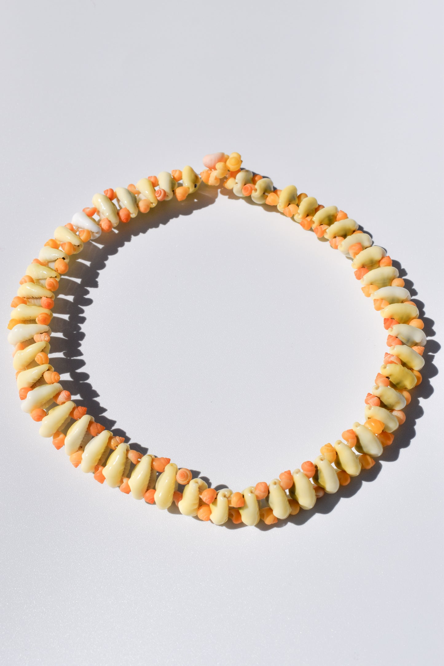 Collier Âme des îles fait main en coquillages naturels, monté sur fil nylon solide. Posé un fond blanc
